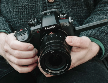 Panasonic Person in sweater holding a black Lumix camera